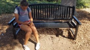 Olivia Starr uses her phone on a school bench.