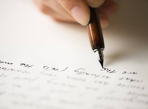 Person writing cursive in black ink.